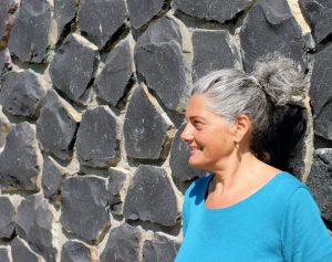 Christine mit Zopf im Profil vor Steinmauer